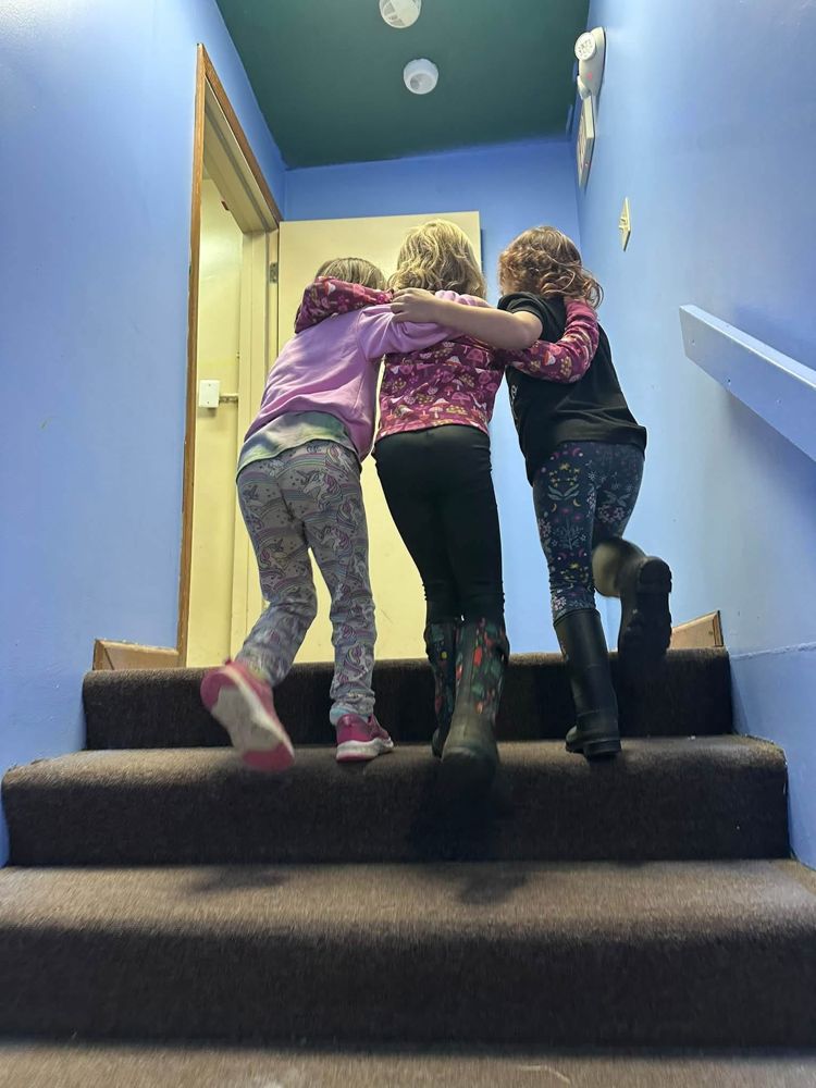 Three co-op kids walking arm in arm up the stairs