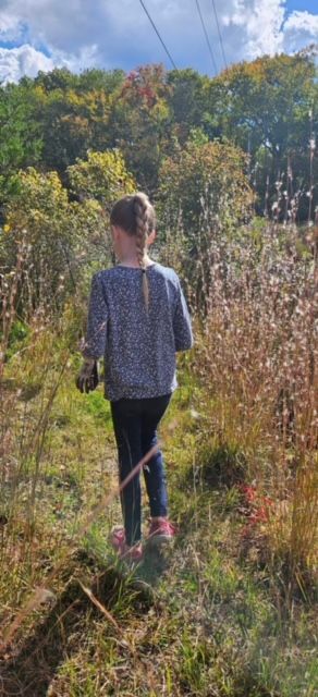 A co-op child walking a meadow trail on a field trip